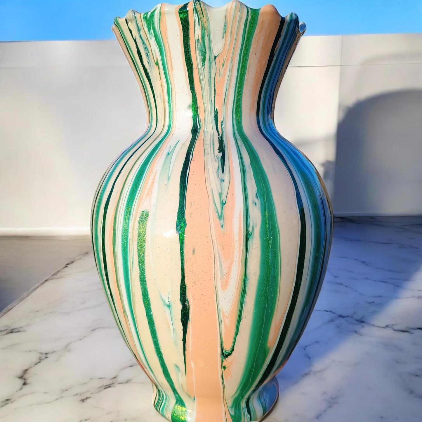 Multicolored striped vase on a marble surface with a blue wall background