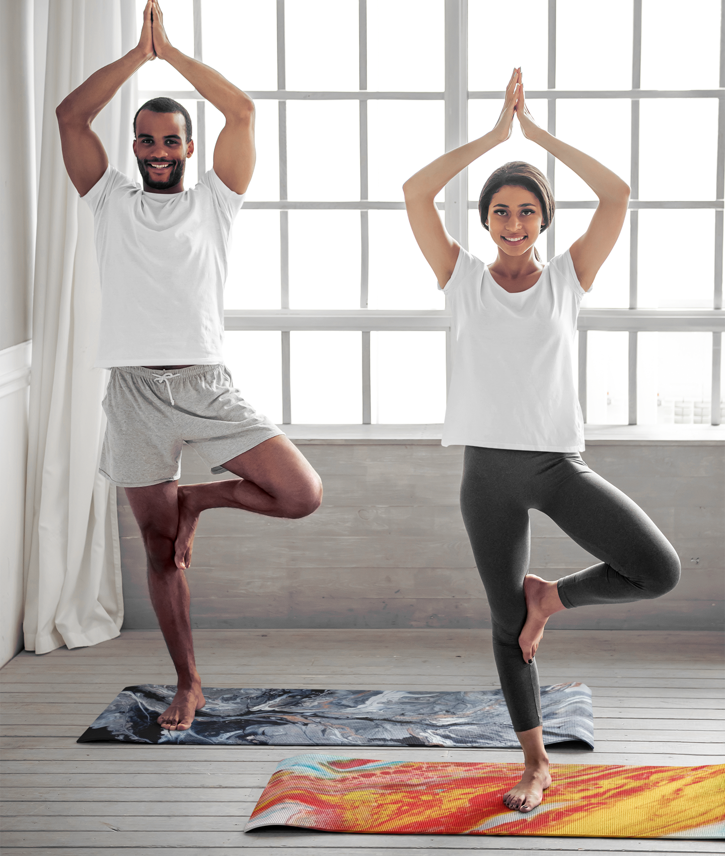 Two people practicing yoga in a bright room with large windows.