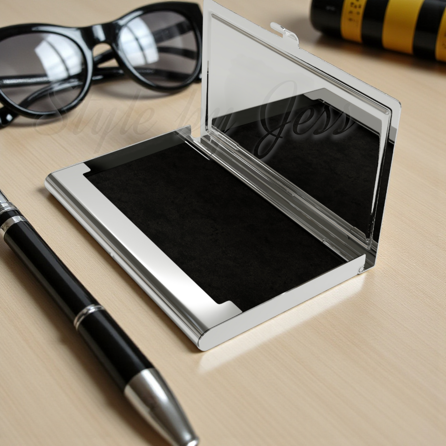 Open business card holder with black velvet interior with sunglasses and pen on a wooden surface