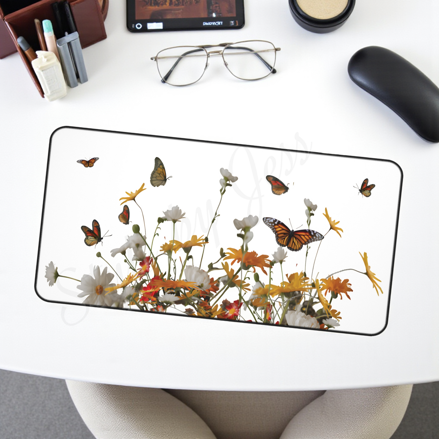 Glass desk mat with floral and butterfly design on a white desk.