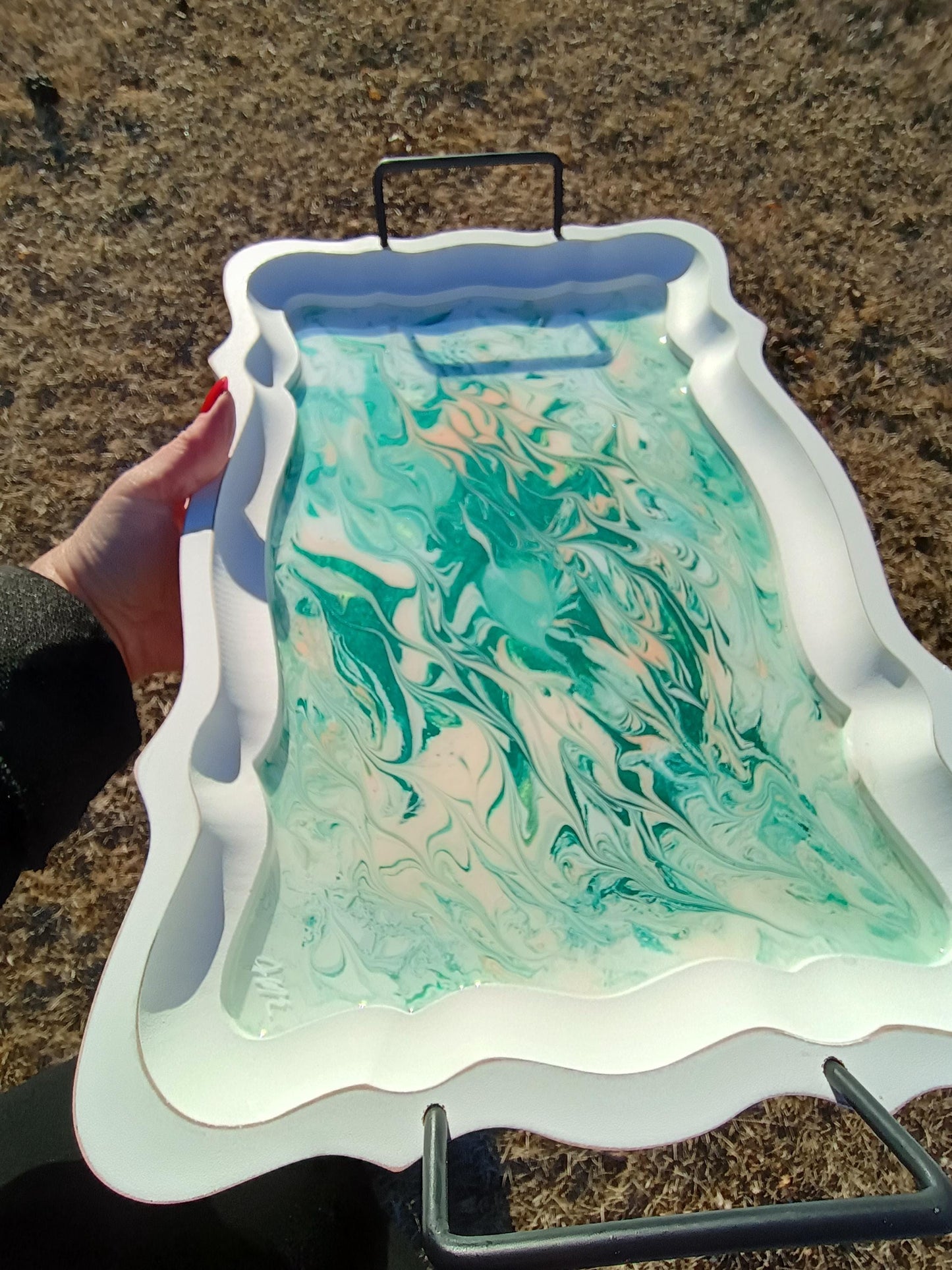 Marbled green and white design on a white tray held by a person outdoors.