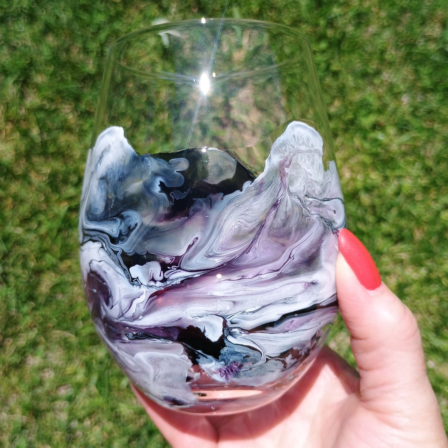 Hand holding a marbled glass against a grassy background