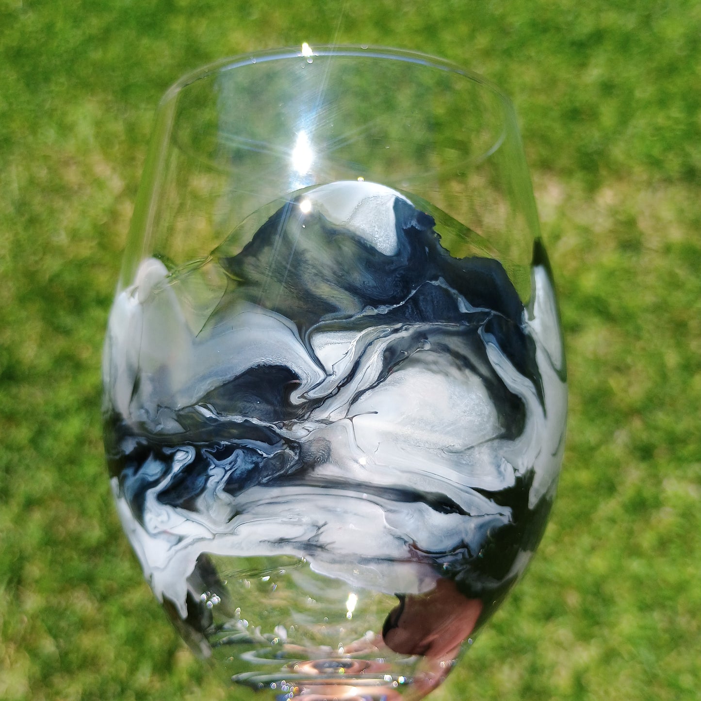 Glass with black and white marbled design on a grassy background