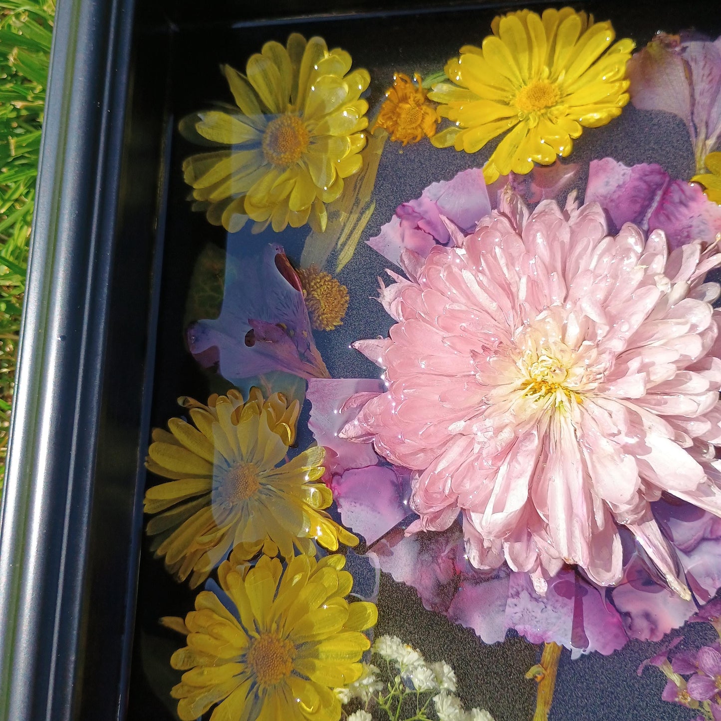Dried flowers including yellow daisies and purple flowers dark surface.