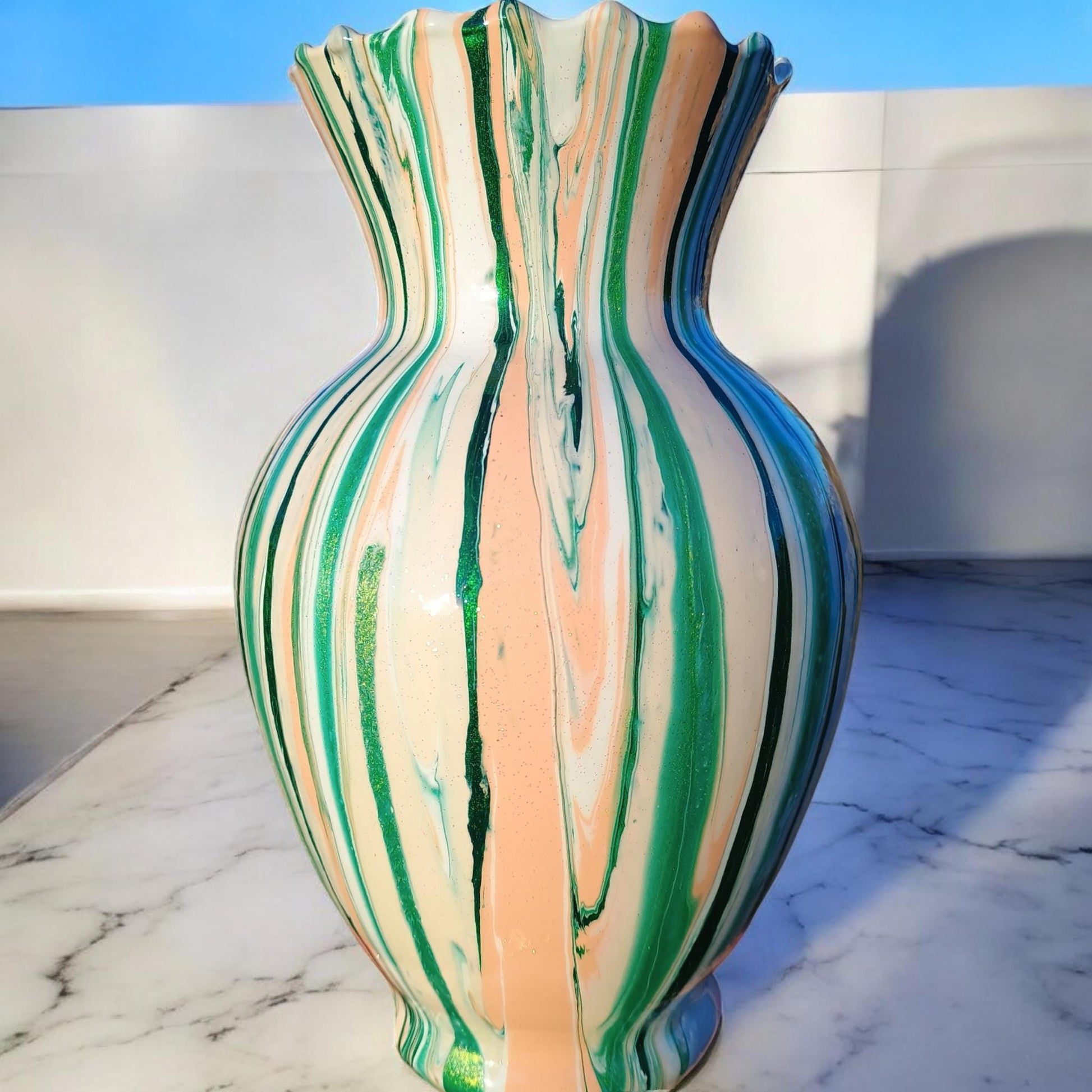 Multicolored striped vase on a marble surface with a blue wall background