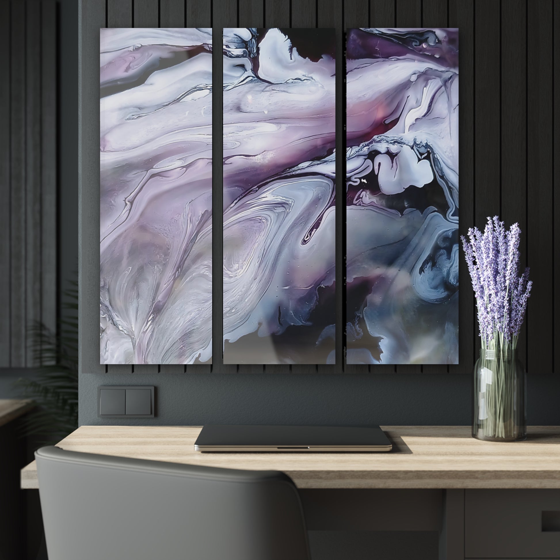 Abstract art triptych on a wall above a desk with a vase of lavender.