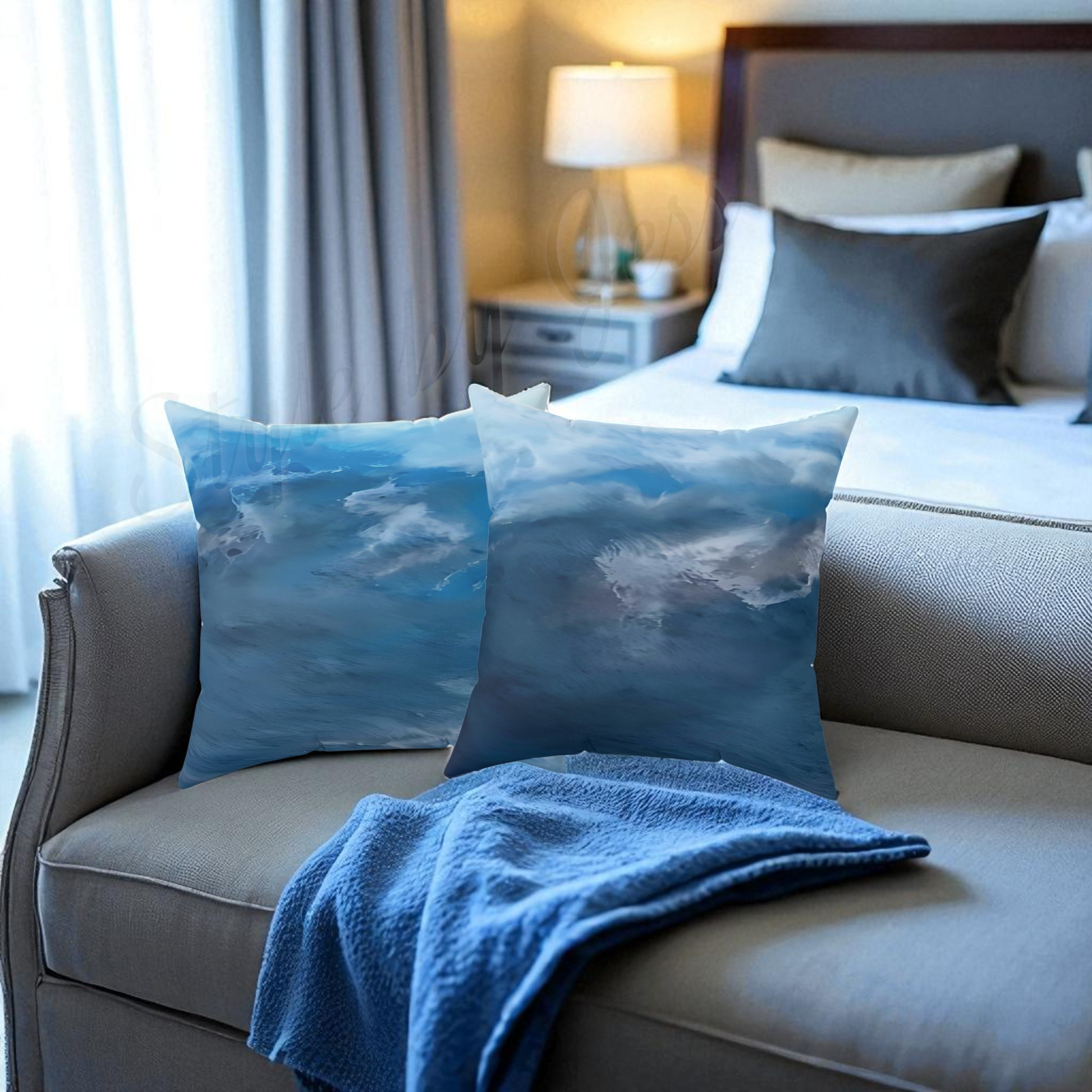Gray sofa with blue cloud-patterned pillows and a blanket in a bedroom setting.