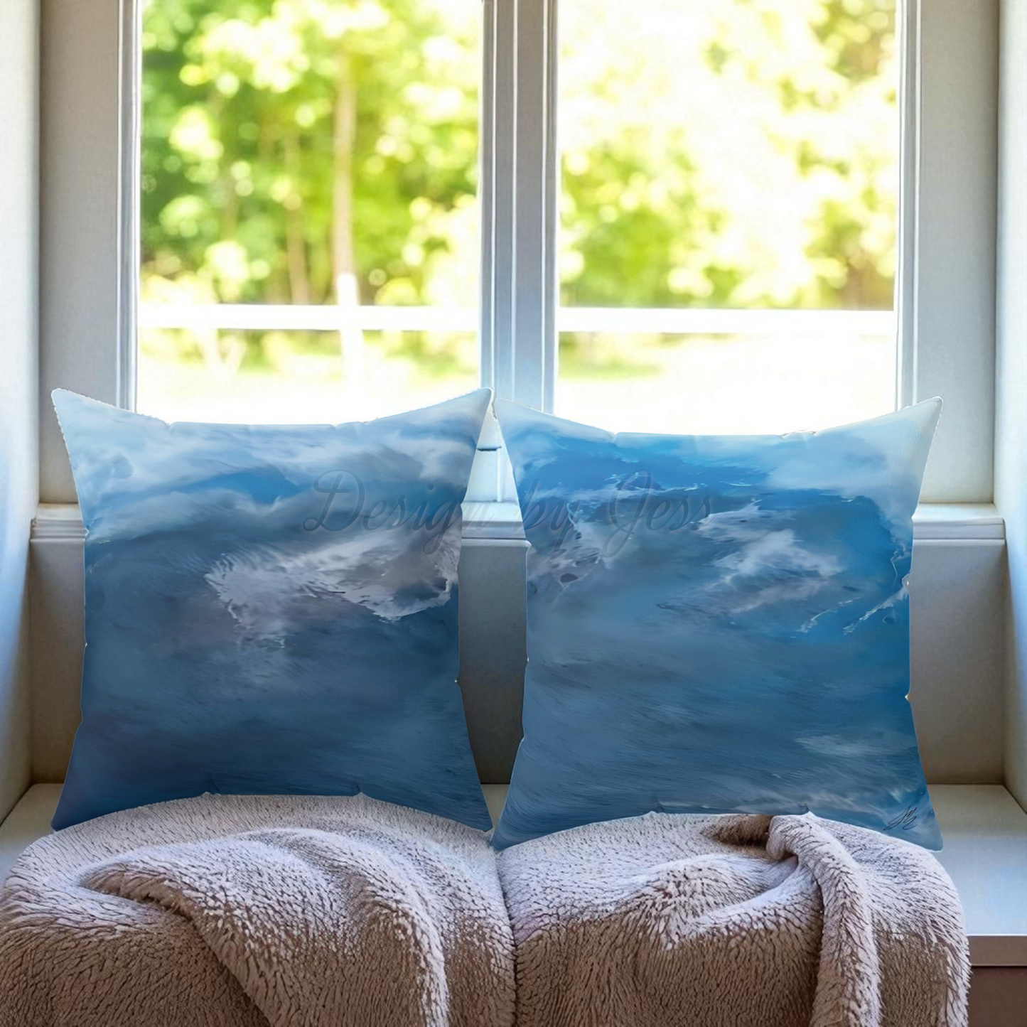 Two blue pillows with a nature design on a window sill with a blurred green outdoor background.