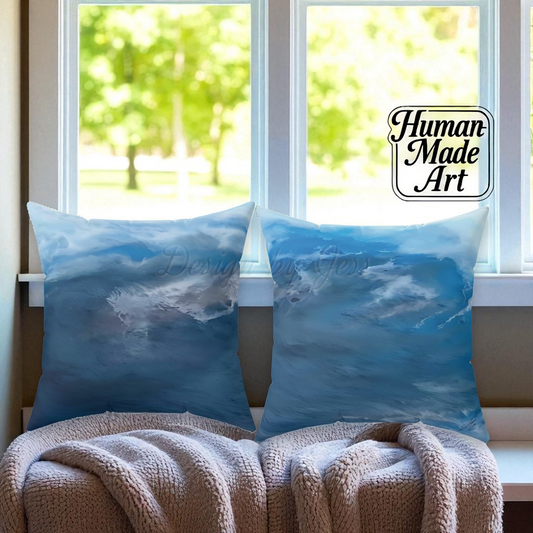 Two blue pillows with a nature design on a couch in front of a window.