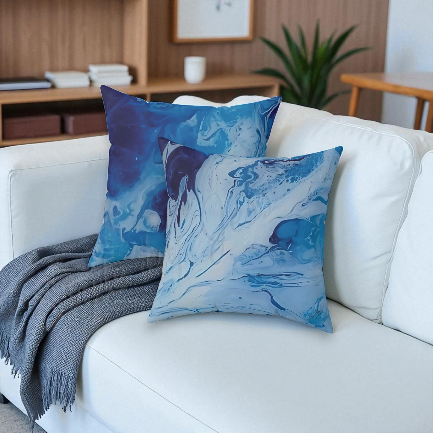 Blue abstract-patterned pillows on a white couch with a gray blanket