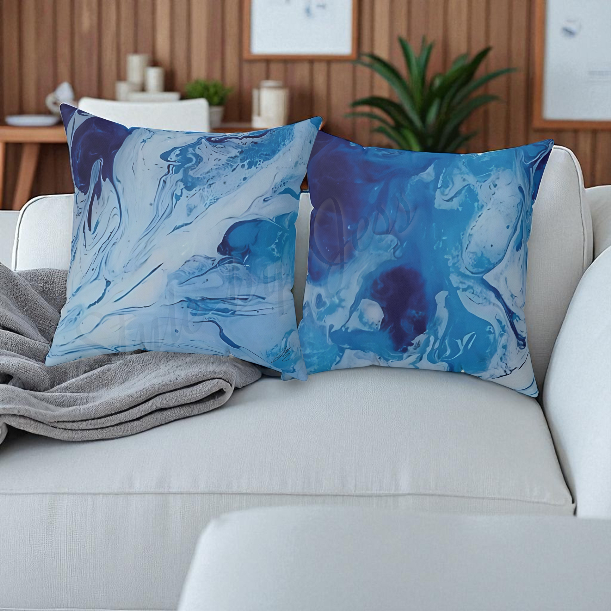 Two blue abstract patterned pillows on a white couch with a neutral background.