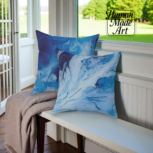 Blue abstract-patterned pillows on a bench with 'Human Made Art' logo.