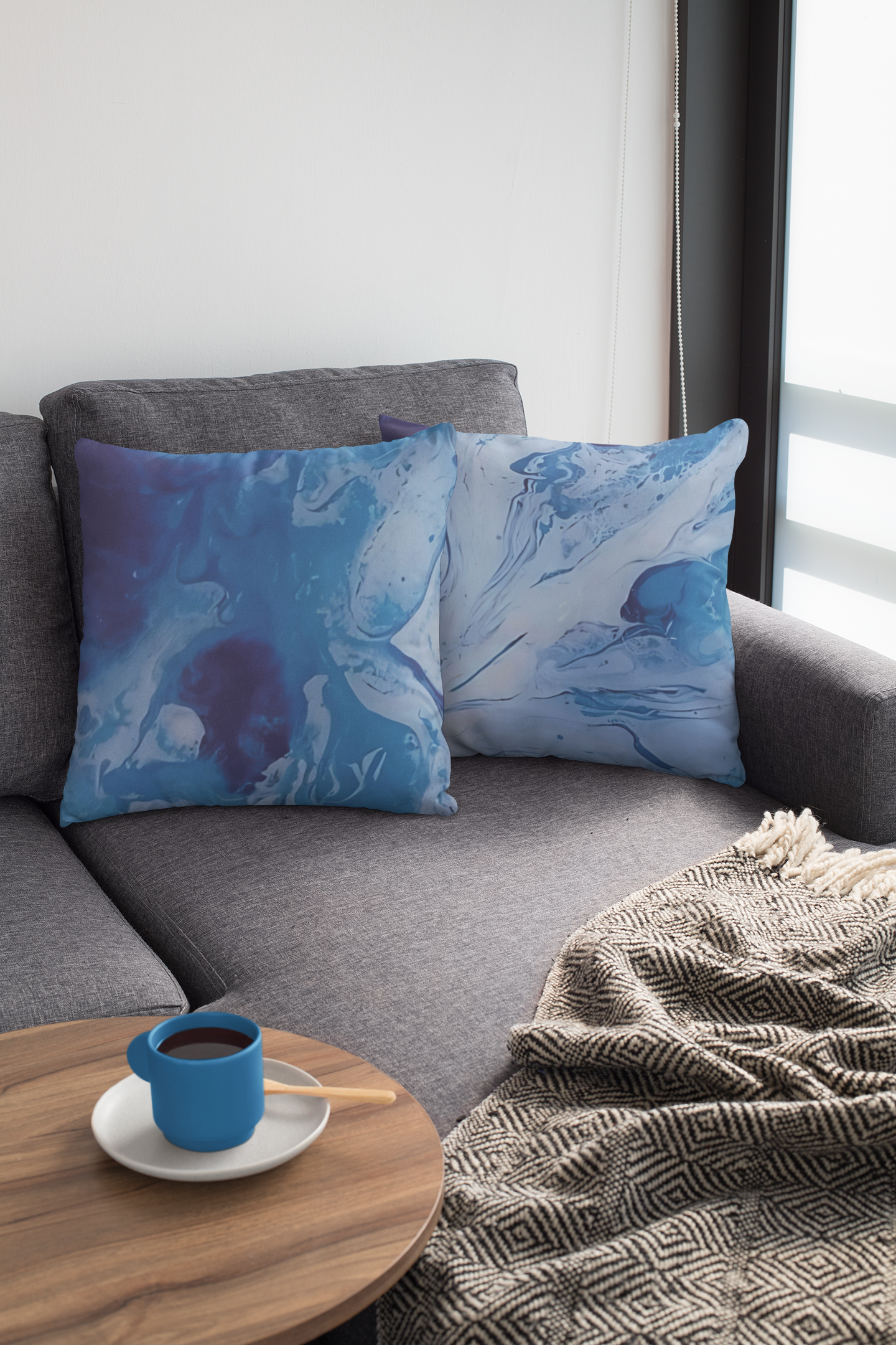 Gray sofa with blue abstract patterned pillows and a cup of coffee on a small table.