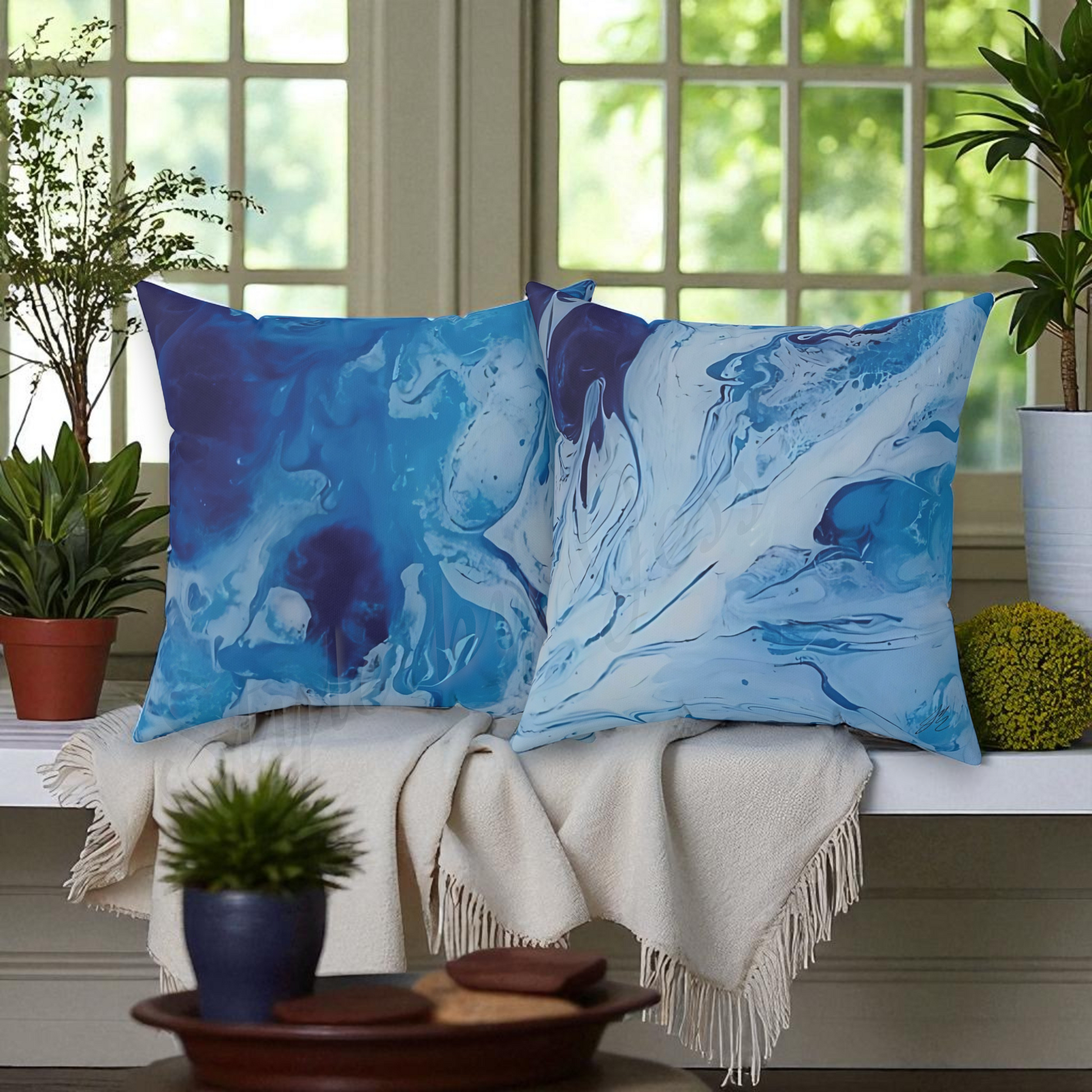 Two blue marbled throw pillows on a couch with plants and decor items.