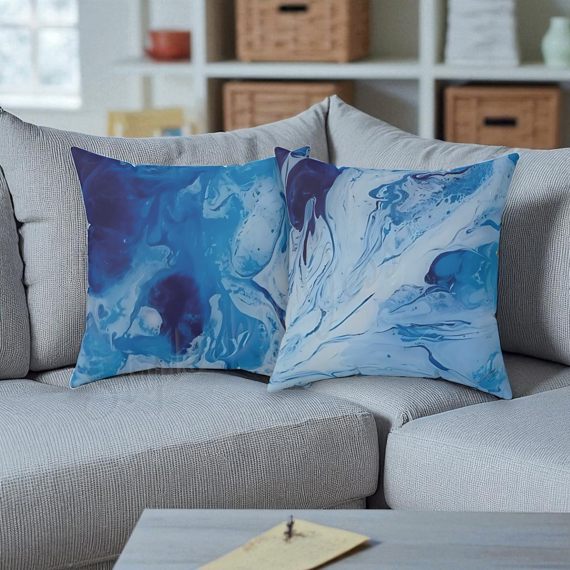 Two blue abstract patterned pillows on a gray sofa with a blurred background.