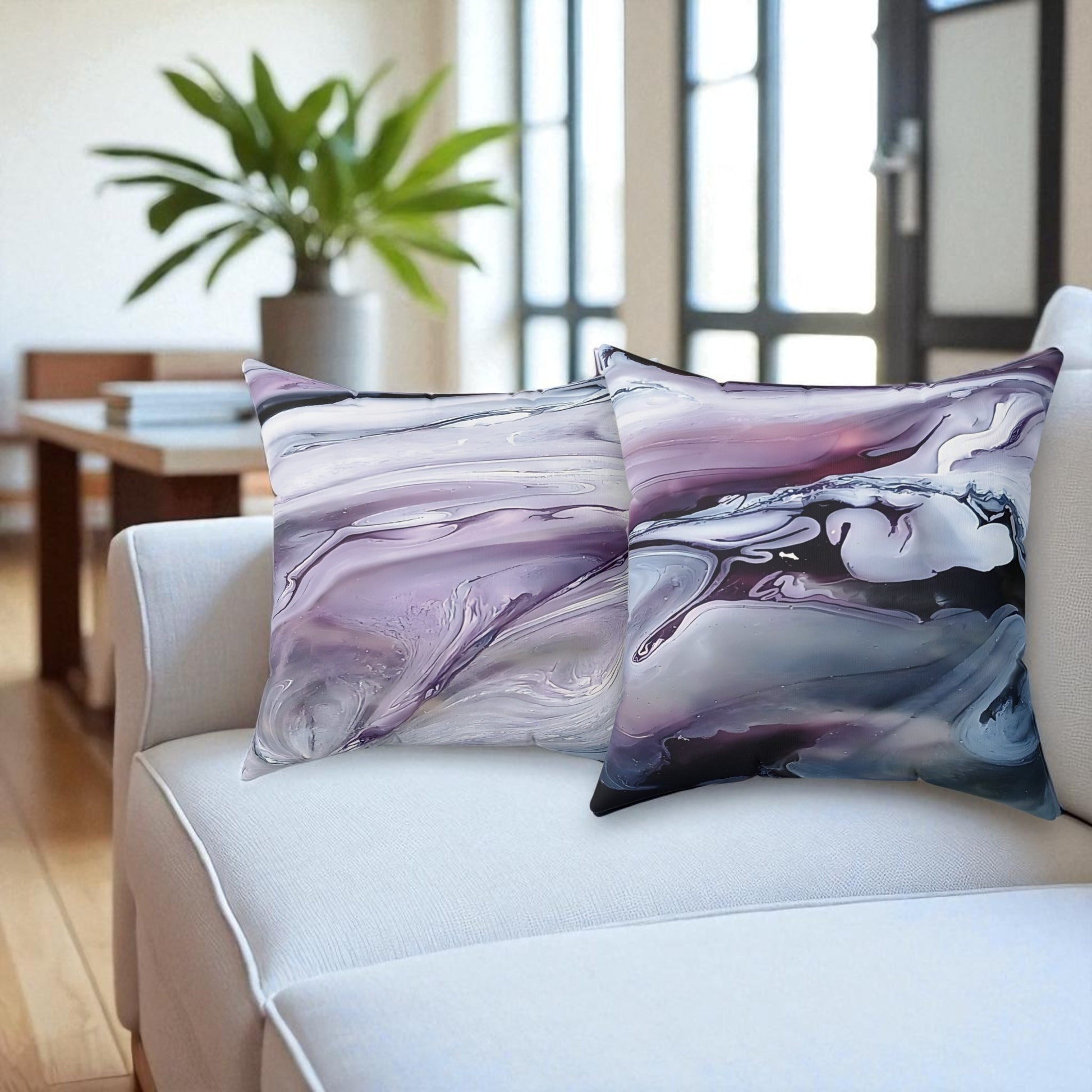 Two abstract-patterned pillows on a white sofa in a living room setting.