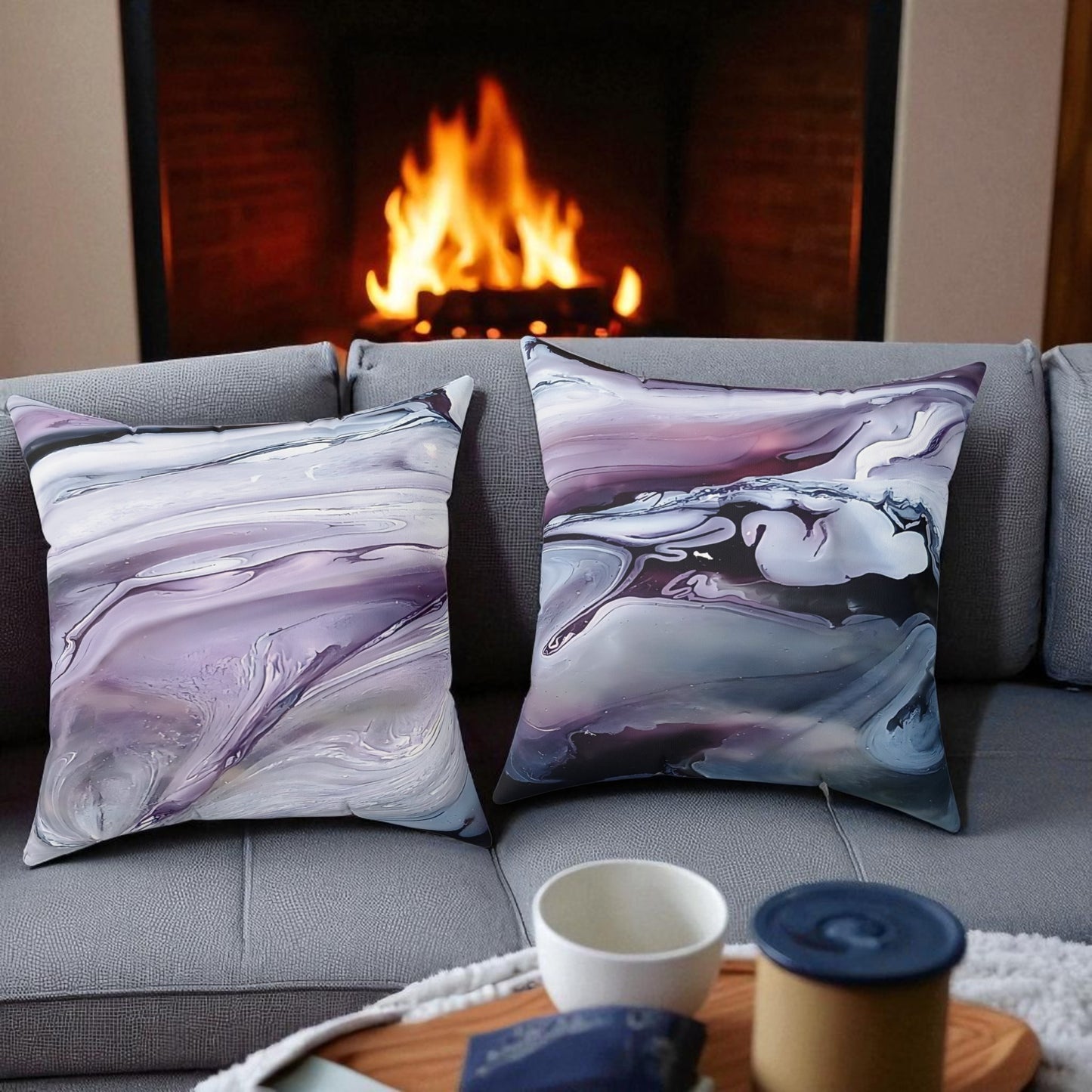 Two marbled patterned pillows on a gray sofa in front of a fireplace.