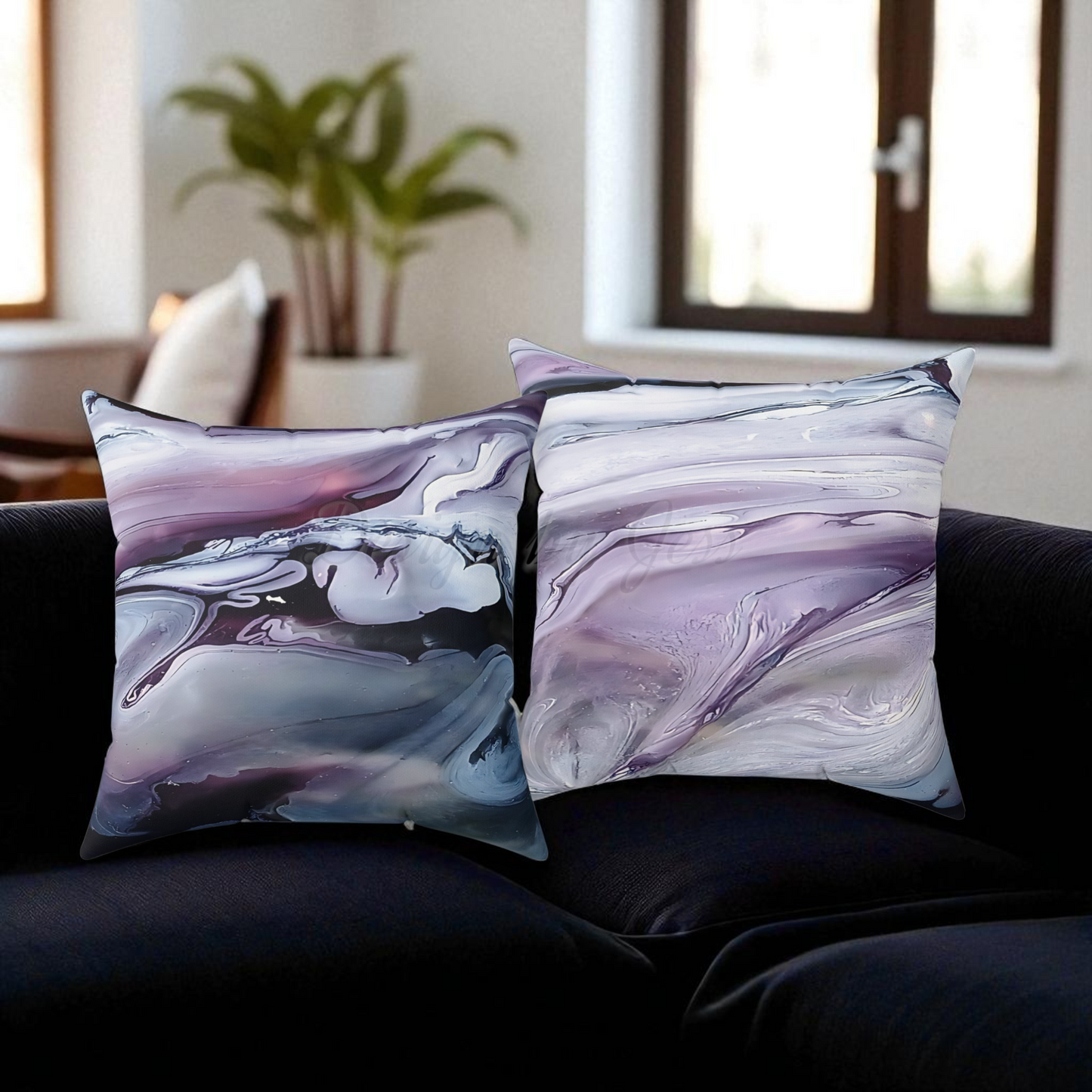 Two abstract-patterned pillows on a dark sofa with a blurred indoor background.