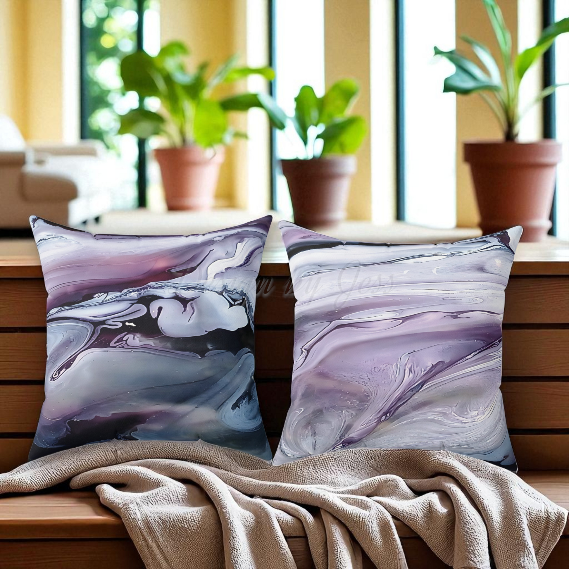 Two marbled patterned pillows on a wooden surface with plants in the background.