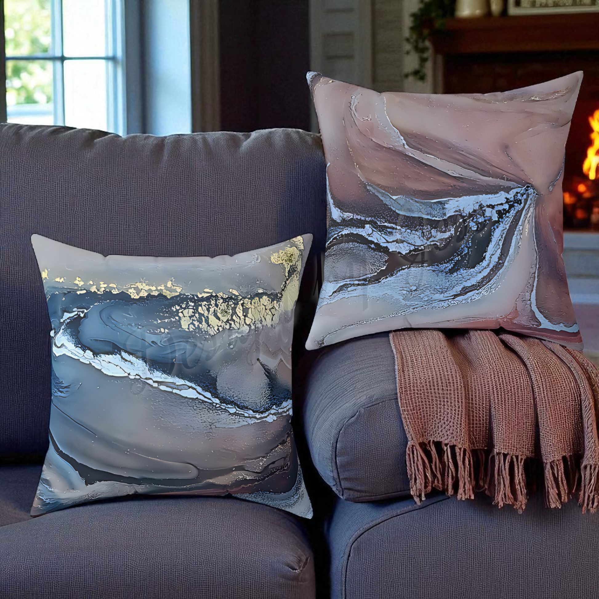 Decorative pillows with abstract designs on a gray sofa with a blanket.