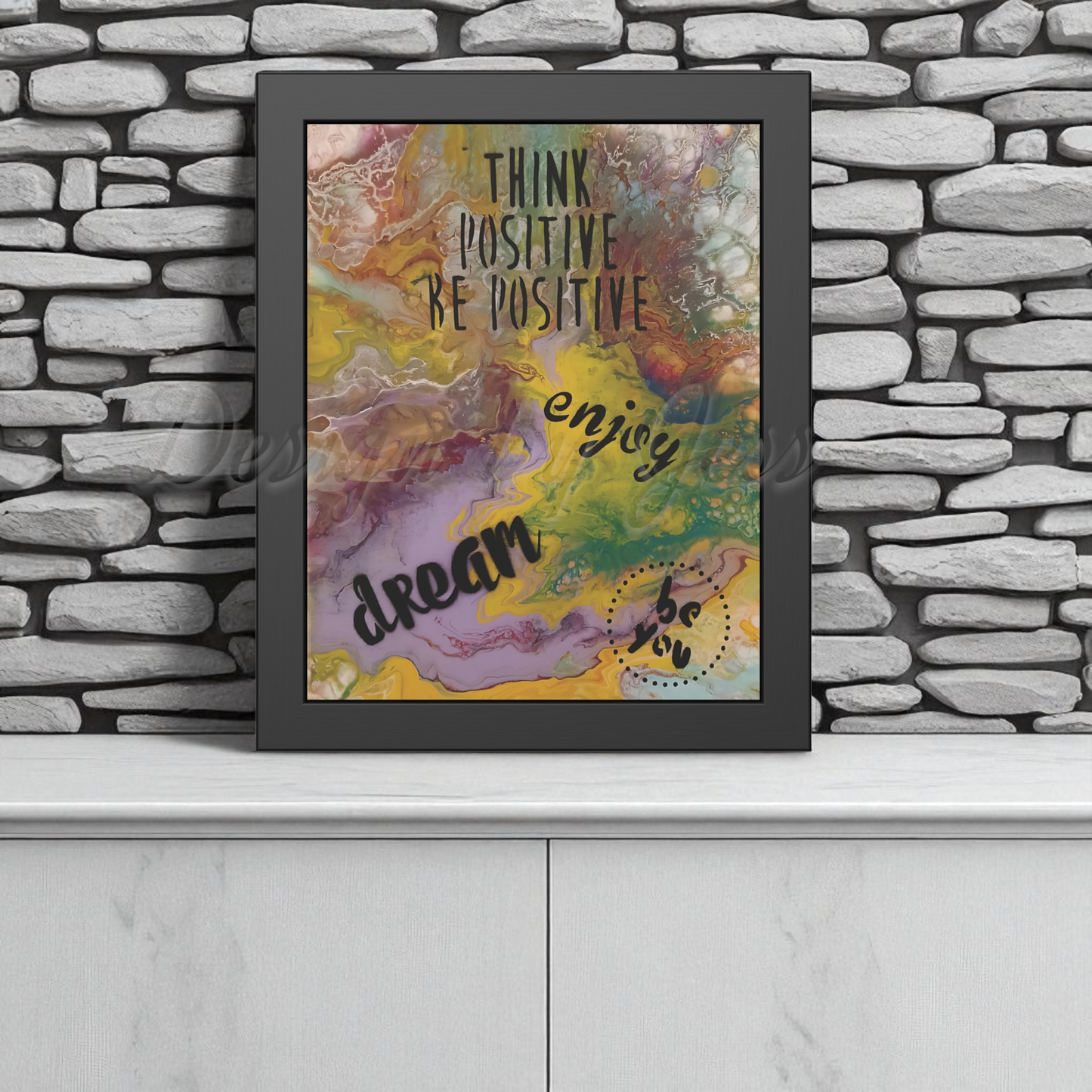 Framed colorful artwork with motivational text on a stone wall background