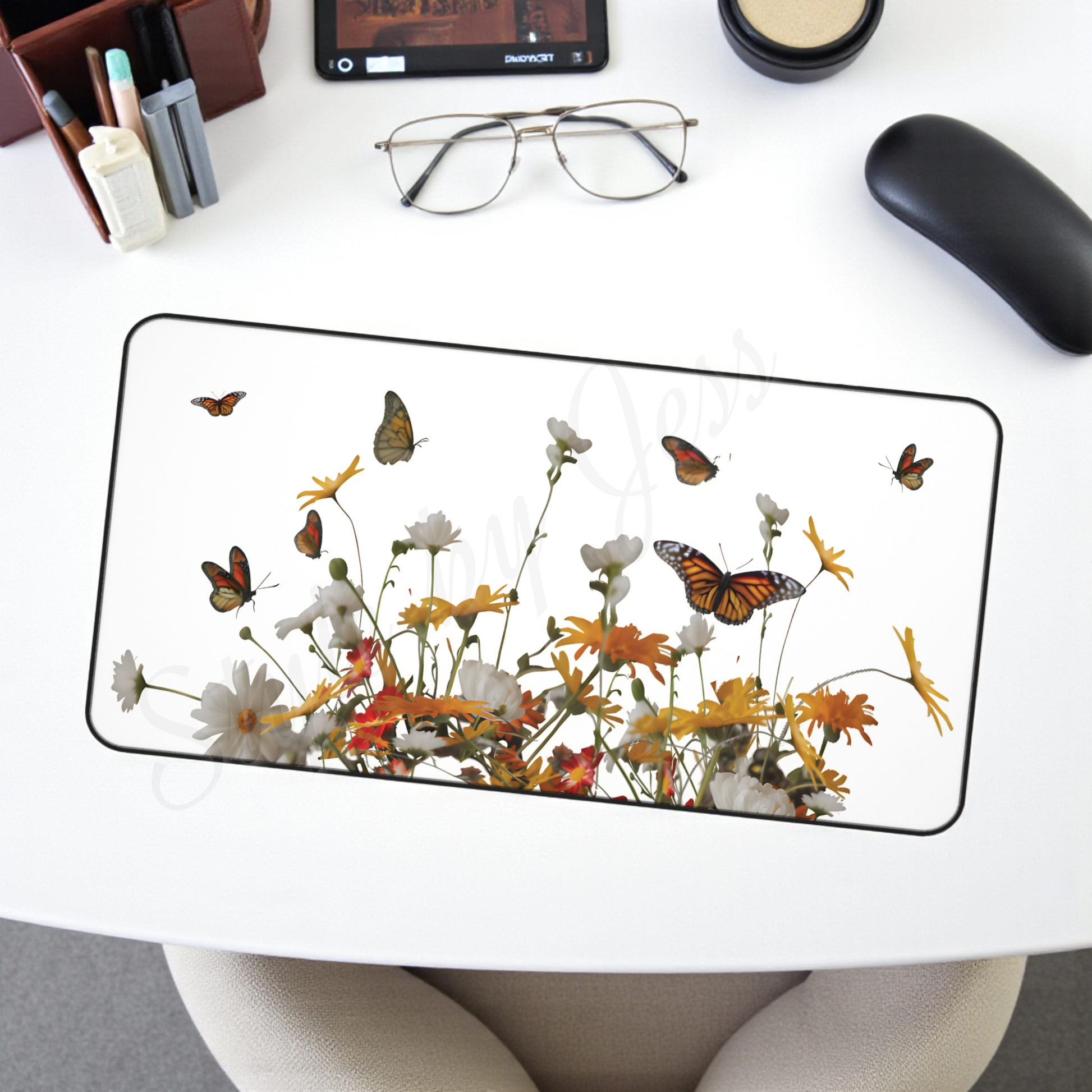 Glass desk mat with floral and butterfly design on a white desk.