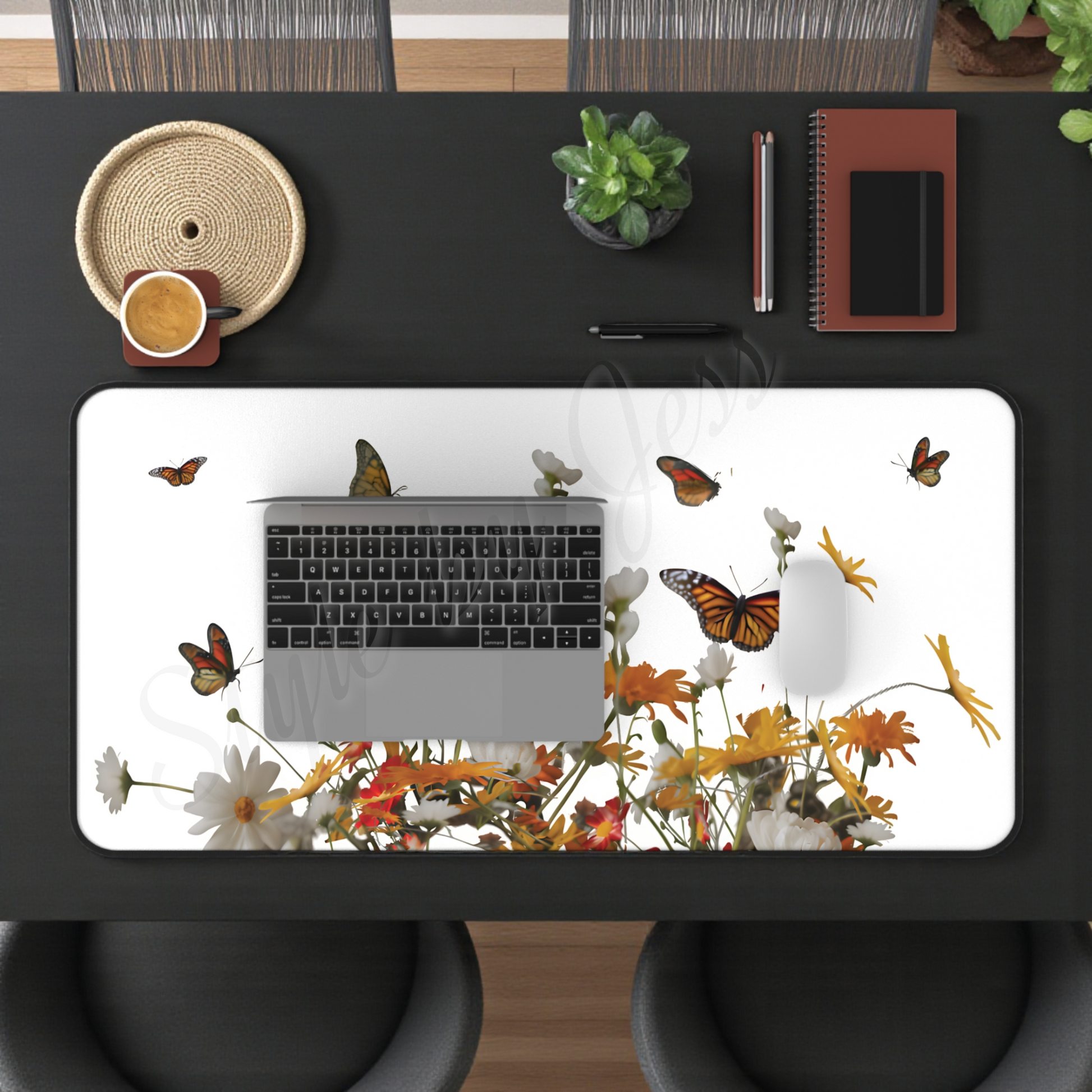 Desk mat with a laptop sitting on it the desk mat has a floral and monarch butterfly design mouse pad, laptop, and office items.