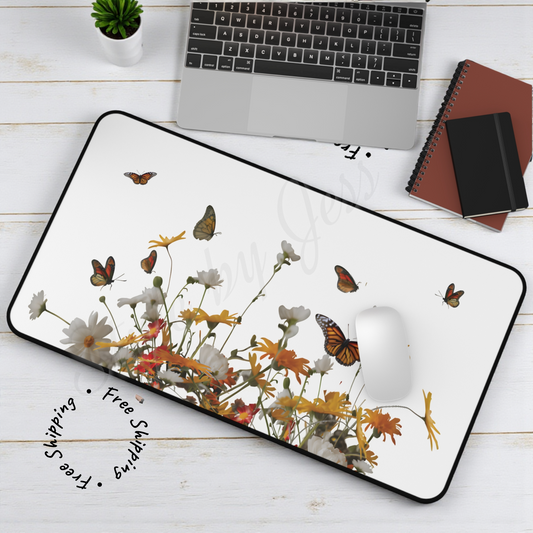 Desk mat with a floral and butterfly design mouse pad, laptop, notebook, and plant.
