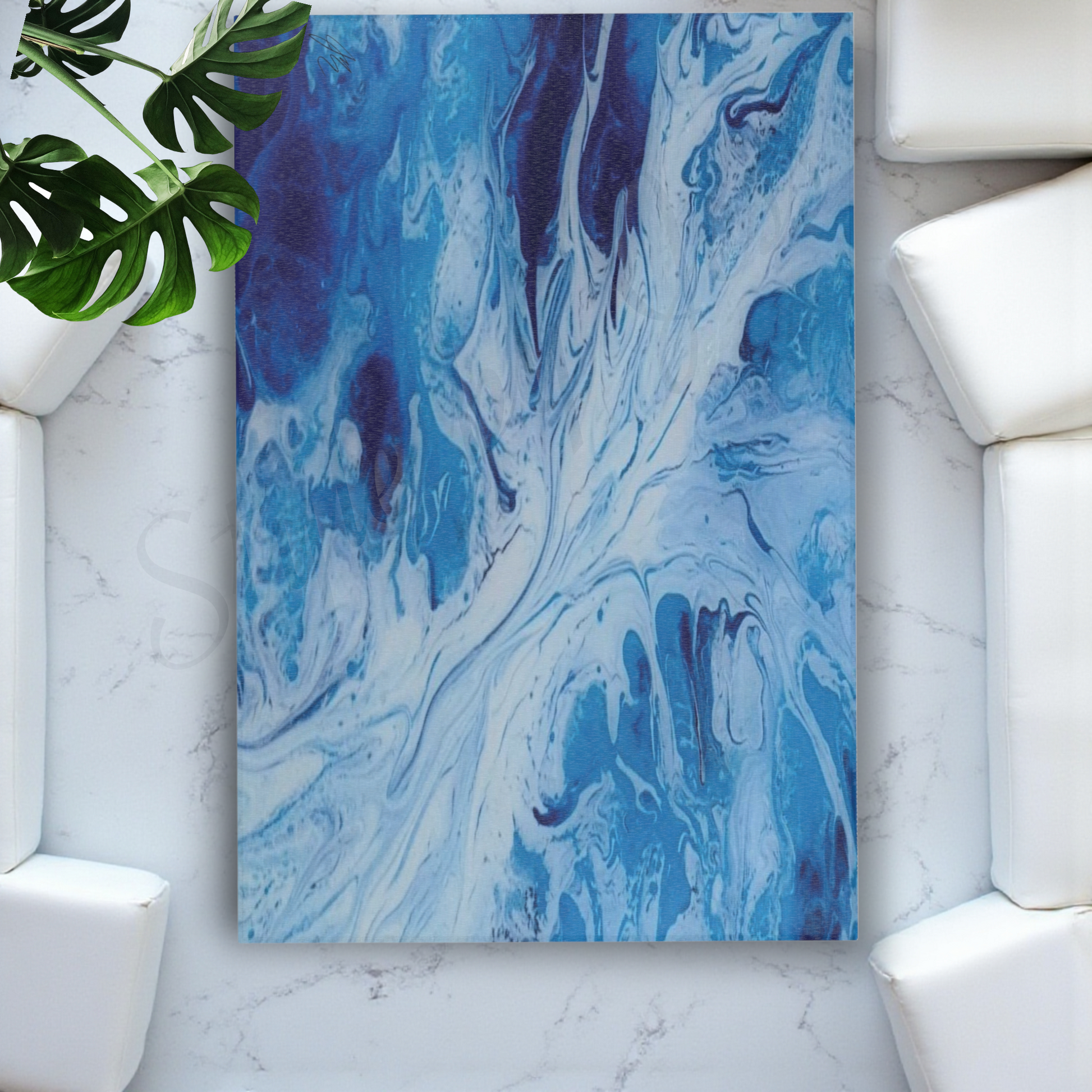 Blue and white abstract painting on a marble wall with a white sofa and green plant.