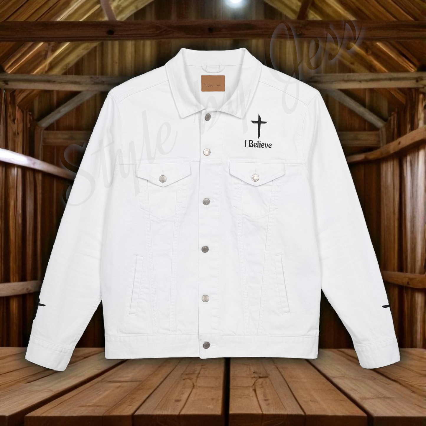 White jacket with 'I Believe' and cross design with a wood barn in the background