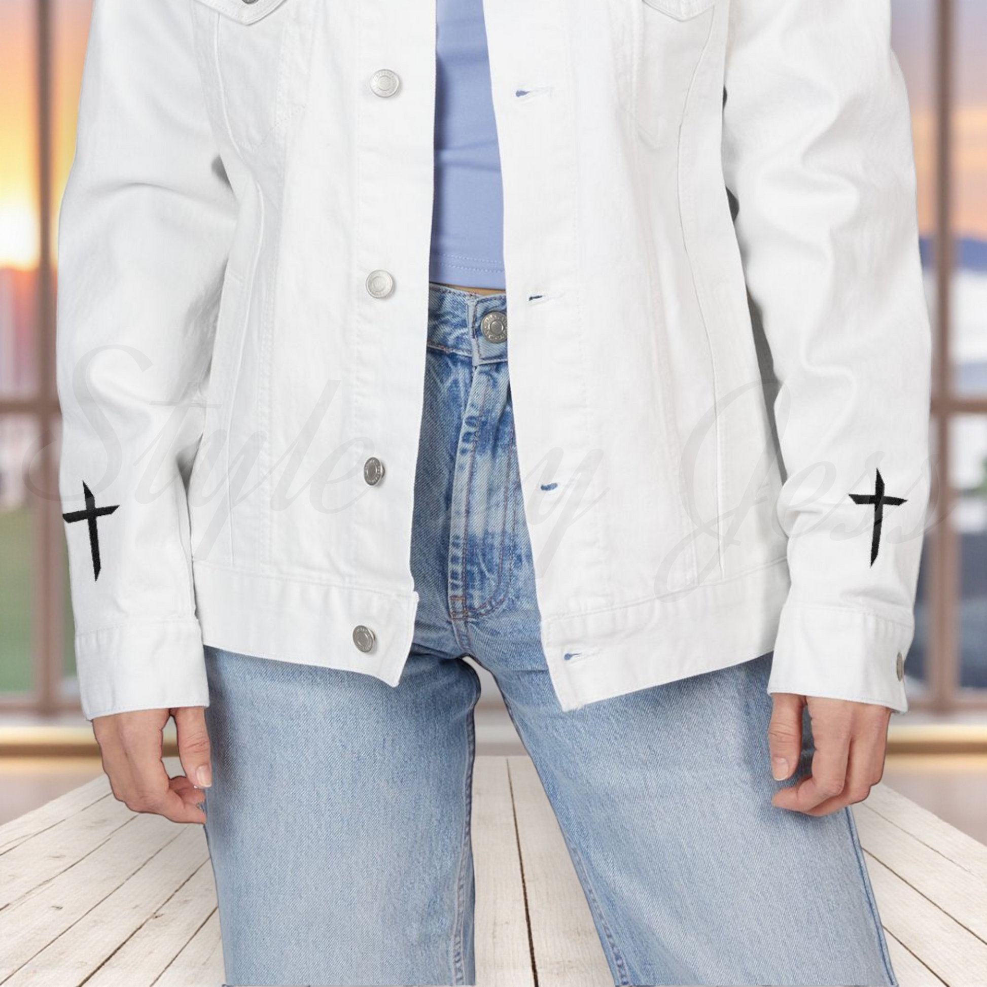 Person wearing a white jacket with black cross symbols on sleeves, standing indoors.