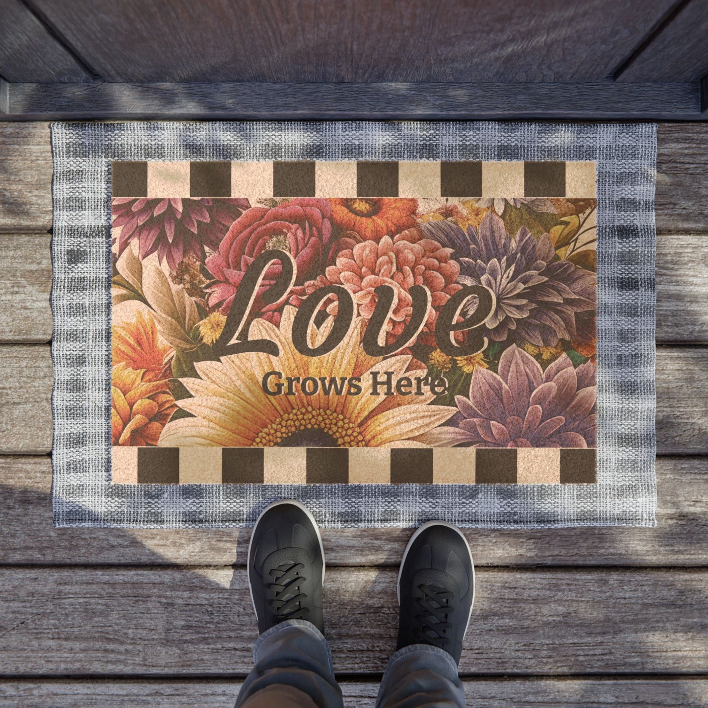Doormat with floral design and 'Love Grows Here' text on a wooden floor.