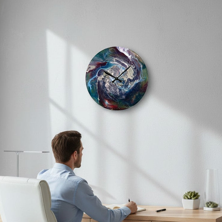 Man sitting at a desk with a colorful wall clock on the wall.