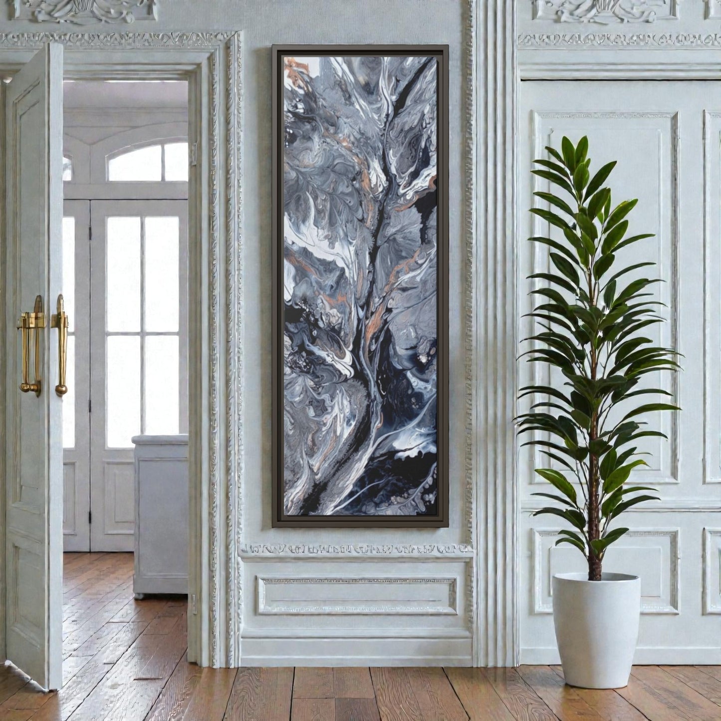 Framed abstract art framed canvas on a wall in an entryway on a narrow wall with a plant in the foreground.