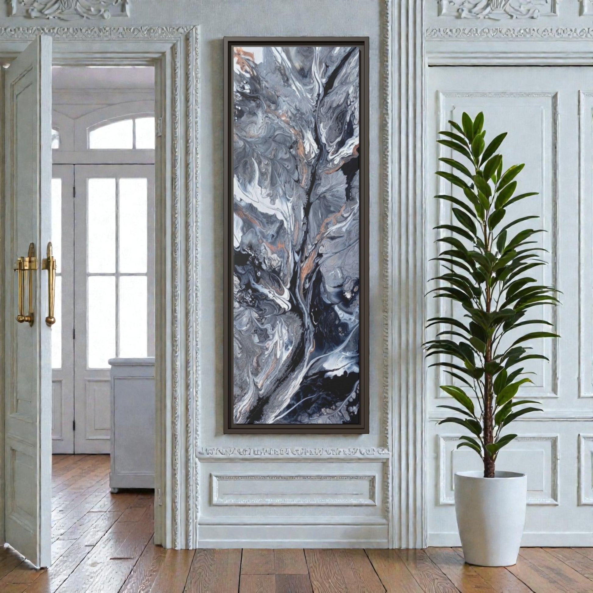Framed abstract art framed canvas on a wall in an entryway on a narrow wall with a plant in the foreground.
