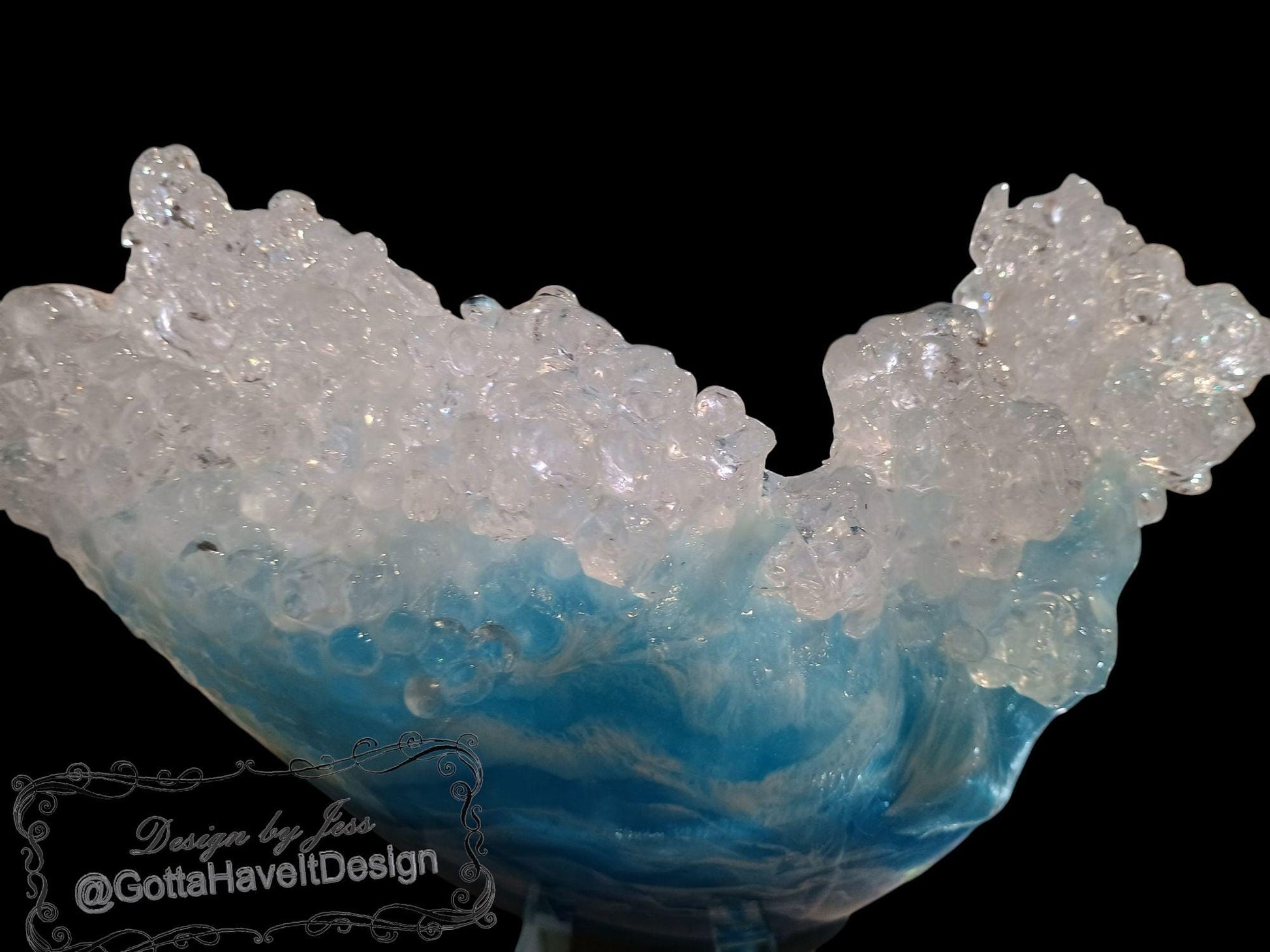 Side view of a resin bowl that shows the waves crashing up on each side with the center lower.  Featuring white at the top and shades of blue and gray at the bottom.  The background is black