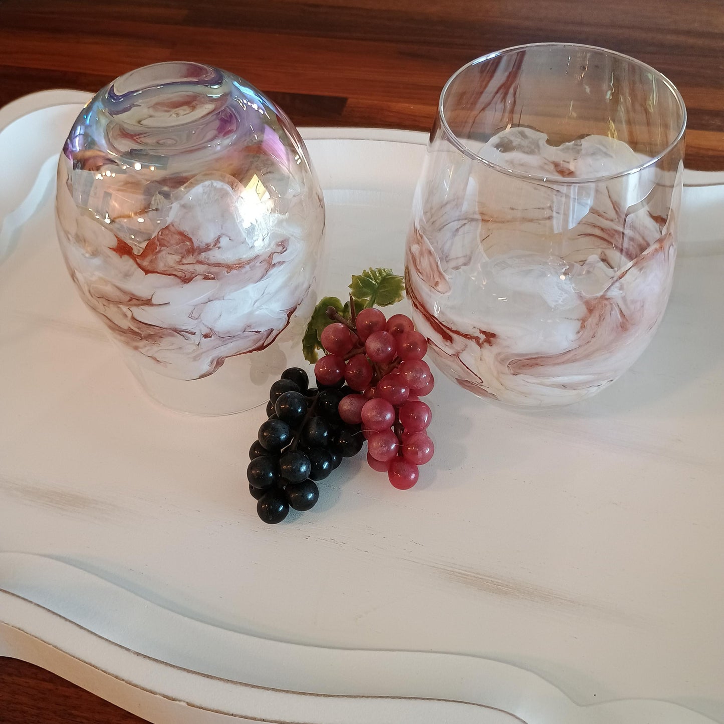 Two marbled glass tumblers with grapes on a white tray.