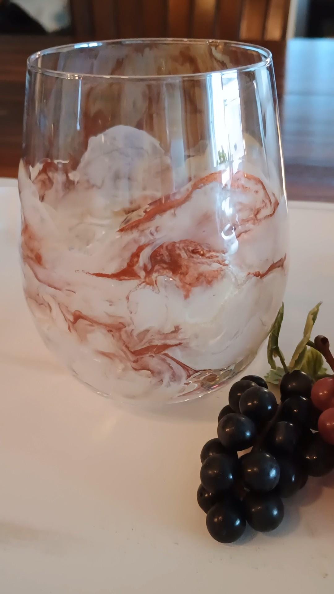 Wine glass with copper and white design on a table with grapes