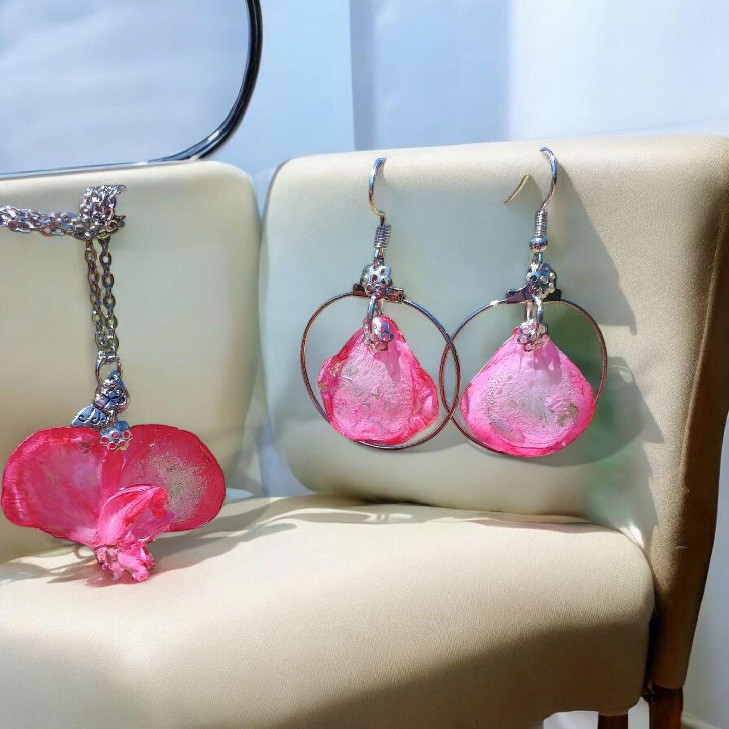 Pink earrings and pendant with silver loops on a beige chair