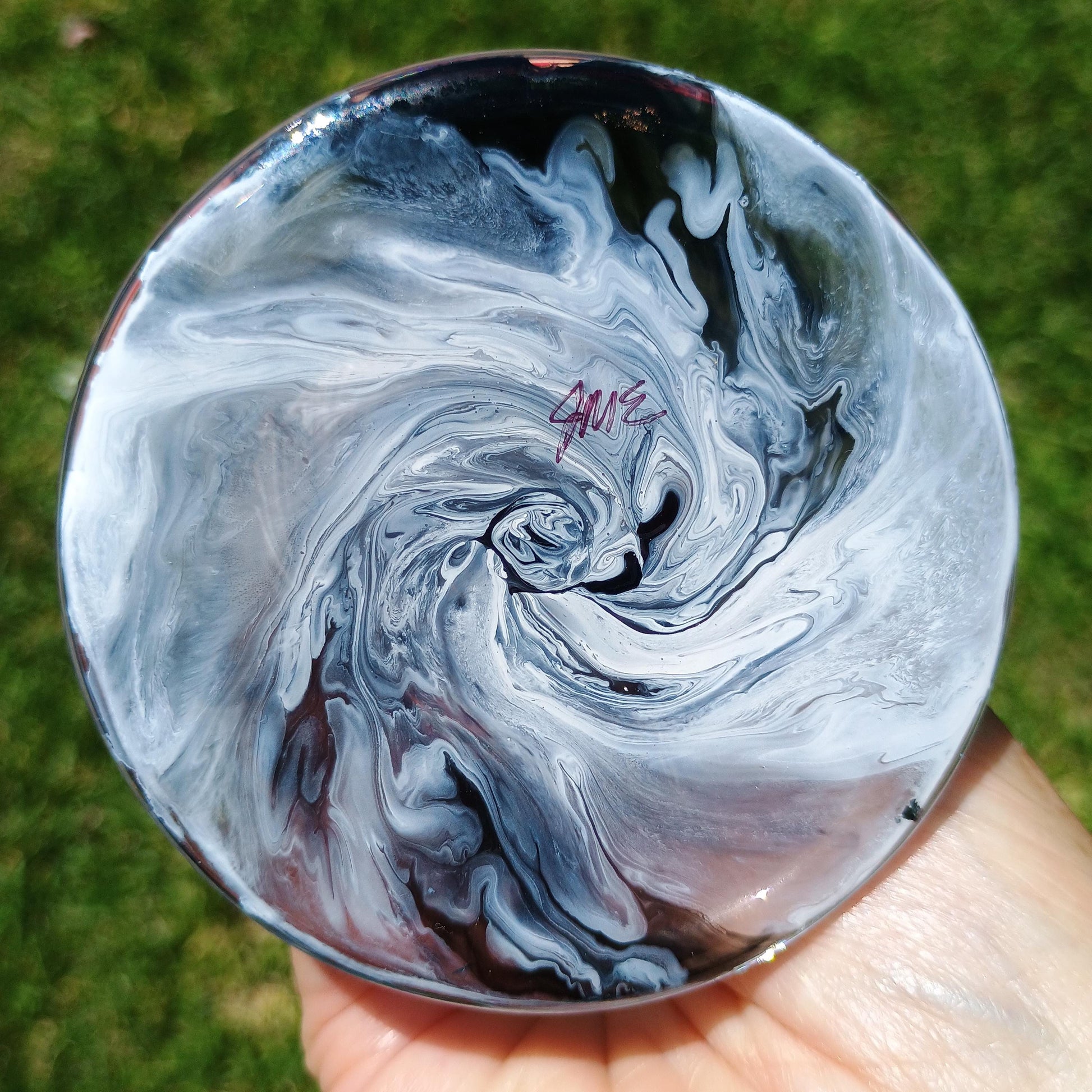 Marbled black and white image of the bottom of the wine glass held in a hand with a blurred green background by Style By Jess