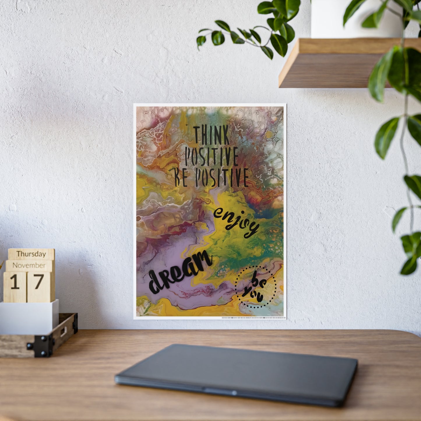 Colorful poster with motivational text on a wall above a wooden desk.
