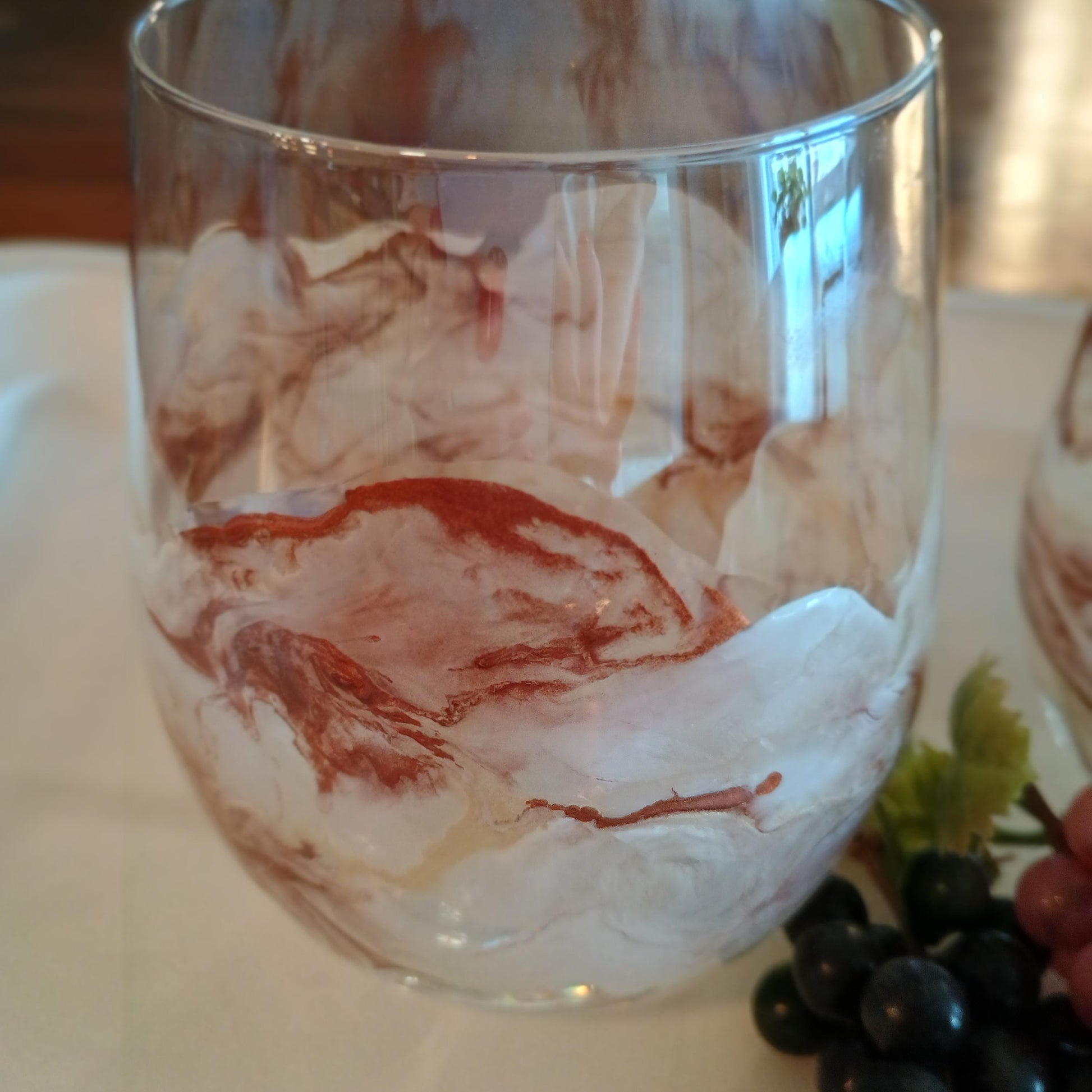 Marbled glass with copper and white design on a white plate with grapes