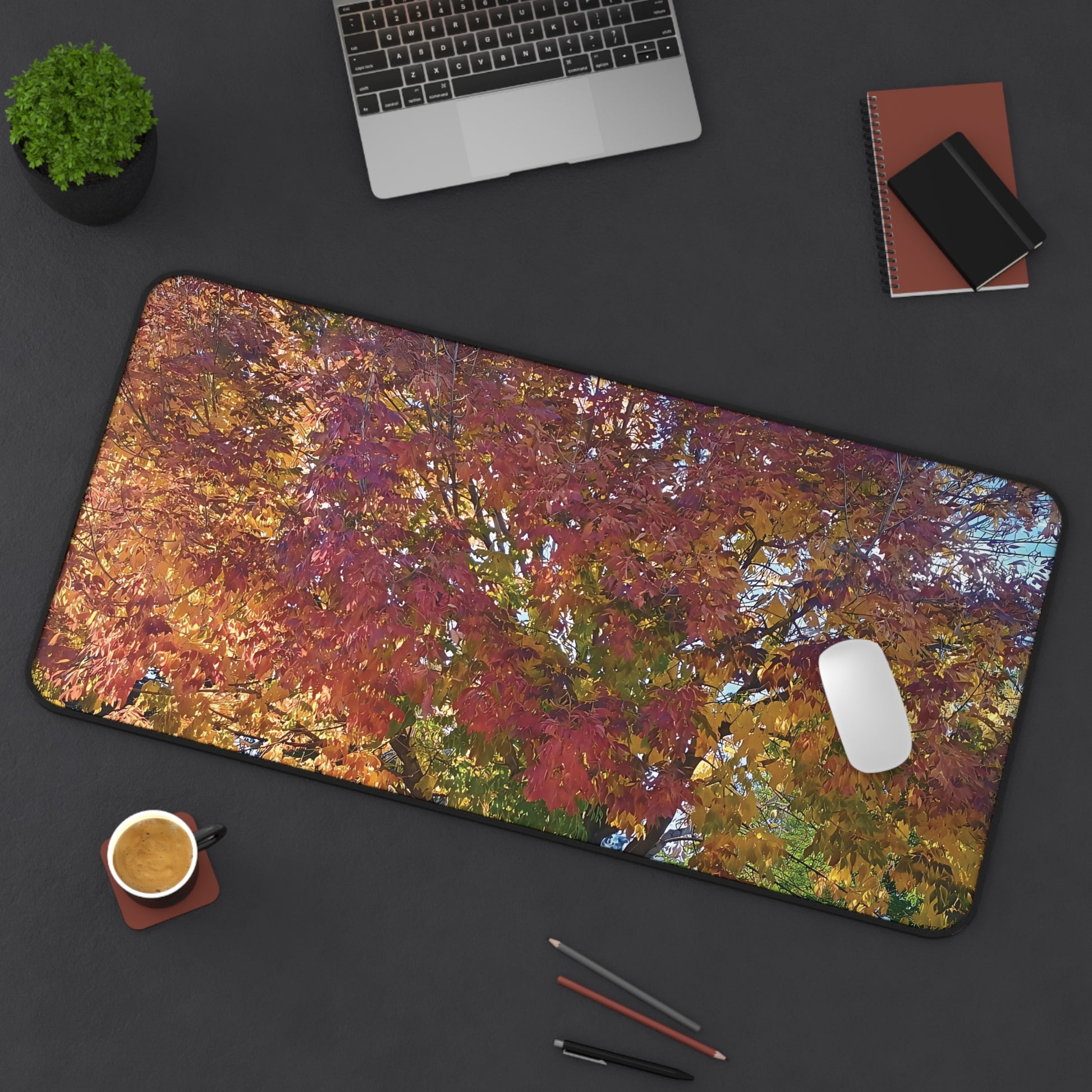 Colorful abstract mouse pad on a desk with a laptop, phone, and other items.