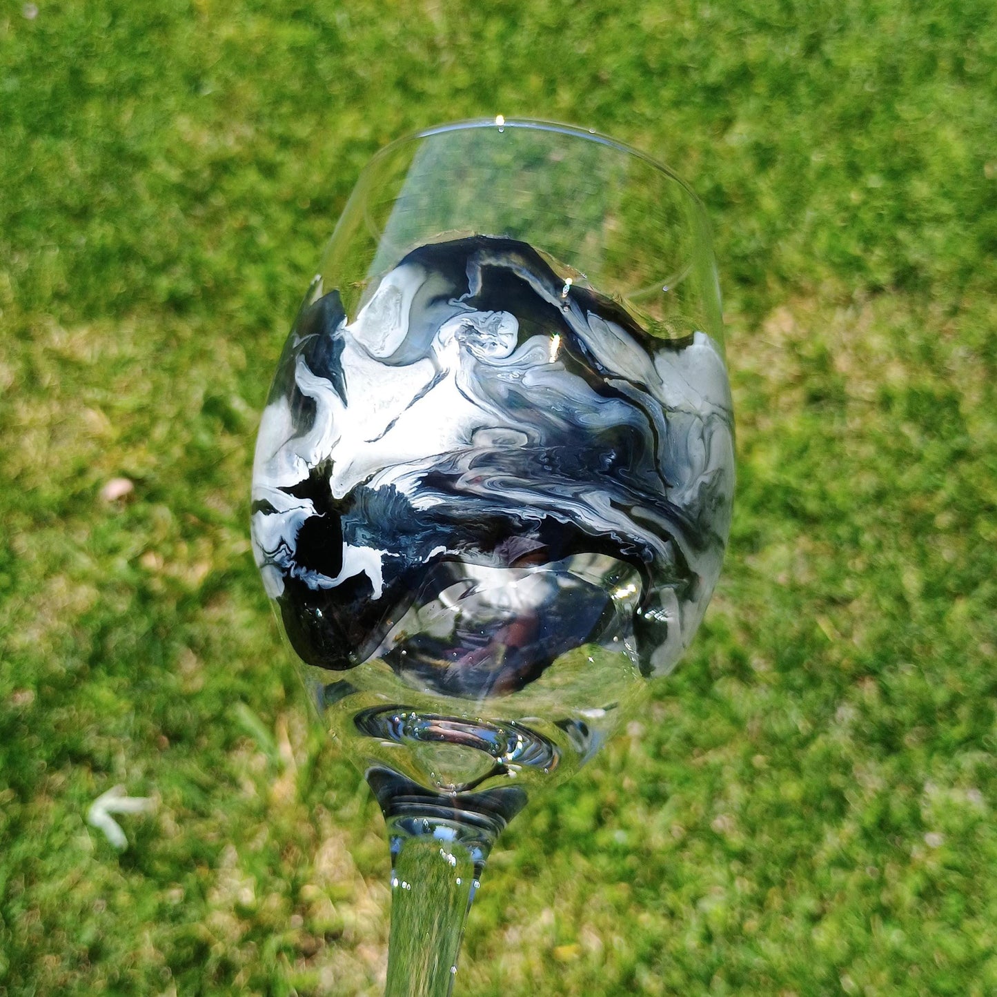 Glass wine glass with black and white marbled design on a grassy background