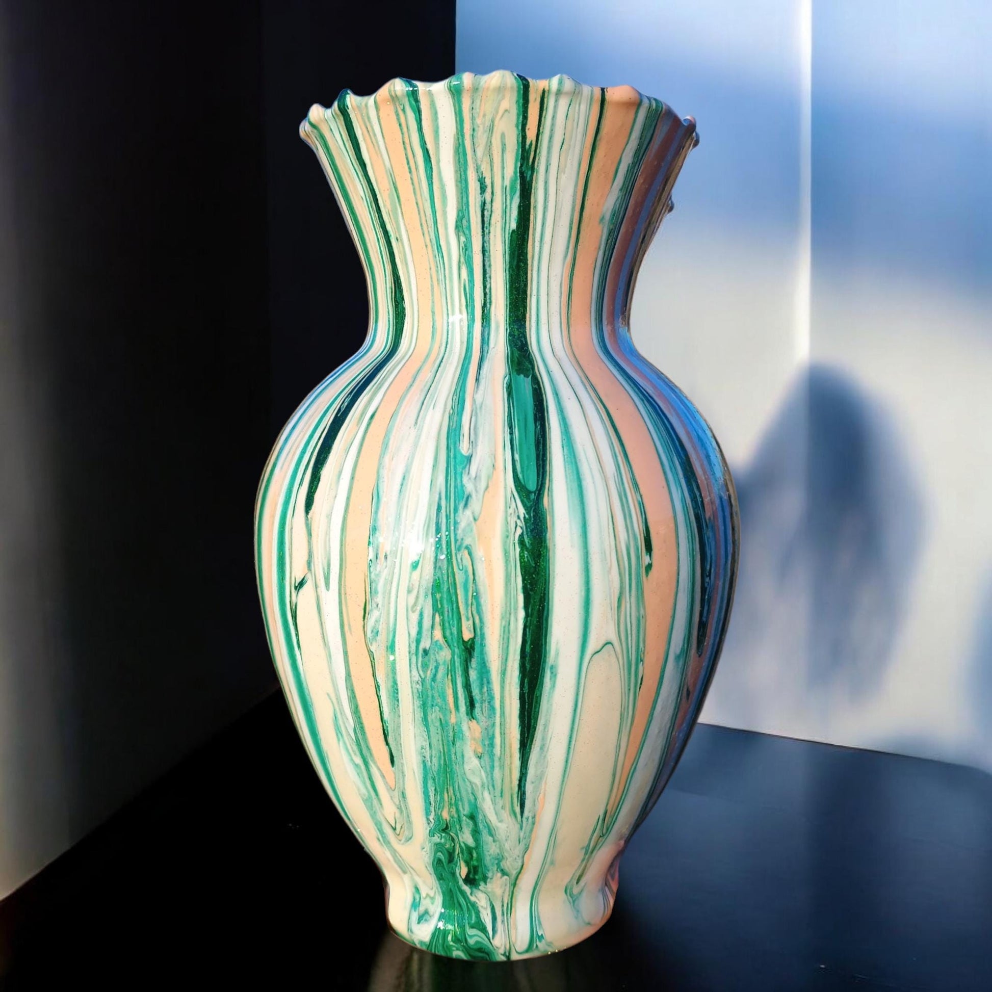 Marbled green and beige vase on a reflective surface