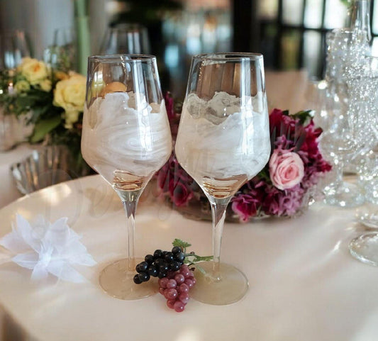 Two decorated wine glasses on a table with flowers and grapes a Style by Jess