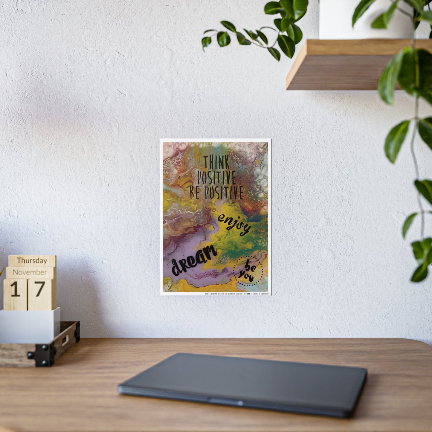 Colorful motivational poster on a wall above a wooden desk with a calendar and plant.