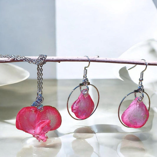 Pink flower petal earrings and necklace with silver loops on a white surface