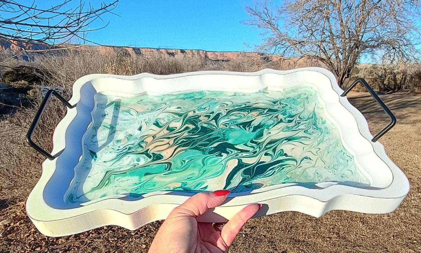 Hand holding a decorative tray with a marbled design against a desert landscape.