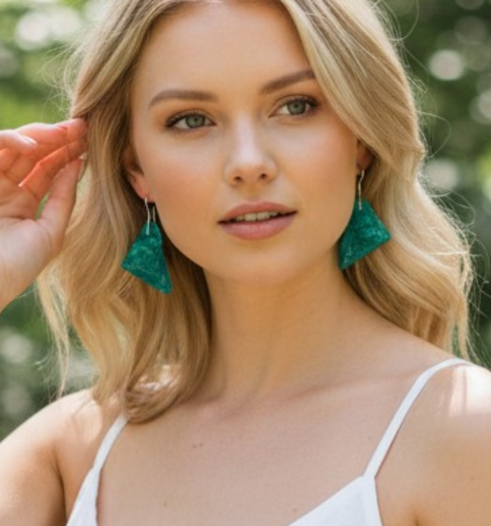 Woman wearing custom artistic blue earrings with a blurred natural background